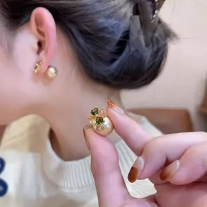 Dettaglio di eleganti orecchini a perla con trifoglio e accenti di zircone verde