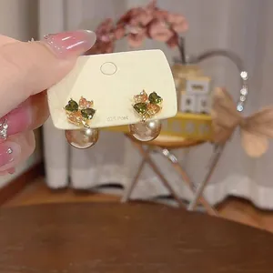 Dettaglio di eleganti orecchini a quadrifoglio in zircone con perle pendenti