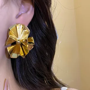 Detailed close-up shot of vintage gold pleated round stud earrings worn on a female model