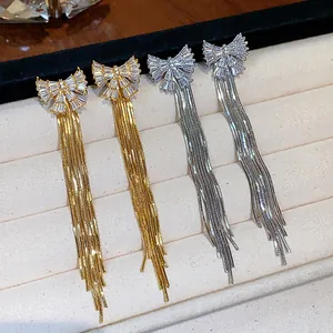 Boucles d'oreilles élégantes à nœud papillon et glands avec zircons brillants en or et argent.