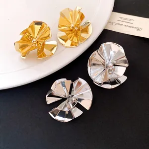 Detail of minimalist crumpled round stud earrings in gold and silver glossy metal finishes