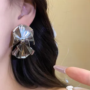 Close-up macro view of silver metallic ruffled spliced stud earrings worn on an ear