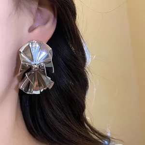 Detailed close-up showing the metallic texture of a vintage pleated silver earring on an ear