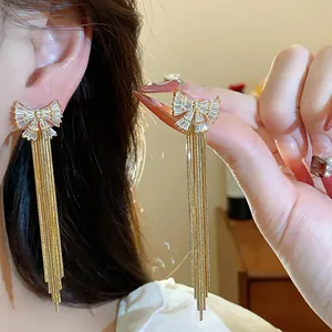 Vue détaillée des boucles d'oreilles nœud en zircon plaqué or 18 carats avec de longs glands