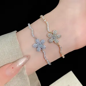 Detailed macro shot of elegant gold and silver zircon flower charm bracelets on a wrist