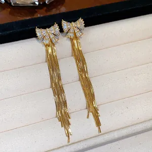 Détail macro de boucles d'oreilles nœud plaquées or 18k avec zircon et longues franges