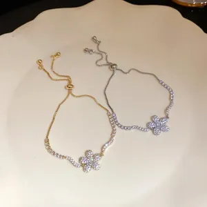 Close-up of elegant gold and silver zircon flower bracelets featuring adjustable chains