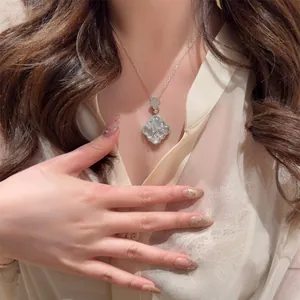 Detail view of silver necklace with white mother-of-pearl lattice pendant on model