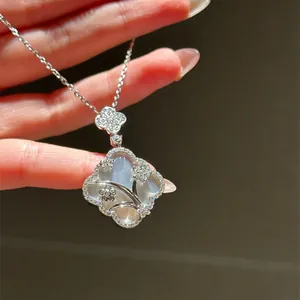 Close-up of white mother-of-pearl window lattice pendant necklace with sparkling stone accents.