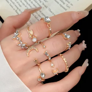 Detail eines 9-teiligen Goldring-Sets mit Herz-, Mond- und Sternanhängern und Kristallen.