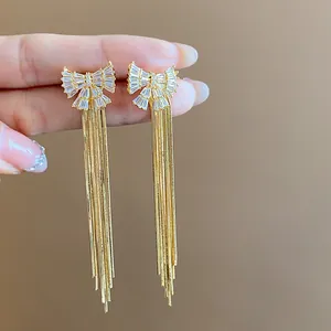 Vue détaillée de boucles d'oreilles plaquées or 18 carats avec nœud en zircon et glands.