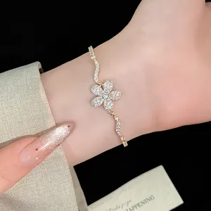 Close-up detail of a sparkling gold-toned zircon flower pendant bracelet worn on a wrist.