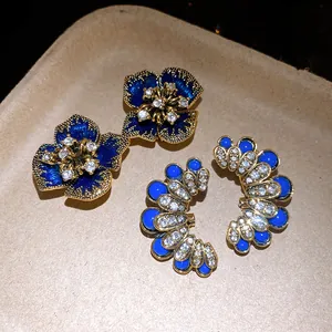 Vintage palace style earrings with blue flowers and rhinestones on tan tray.