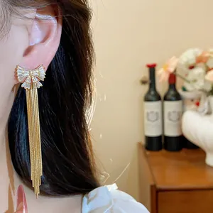 Gros plan élégant de boucles d'oreilles nœud plaquées or 18 carats avec longs pompons en zircon