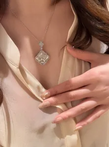 Detailed close-up of a white mother of pearl necklace with floral engraving on a model