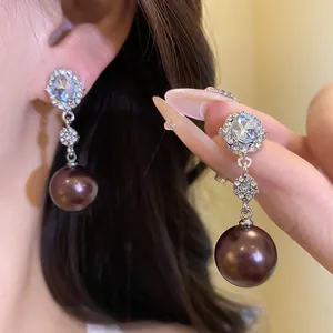 Close-up of elegant S925 silver needle earrings with oval crystals and brown pearls