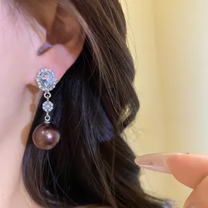 Detailed view of elegant silver earrings with dark pearl pendants and oval stones.