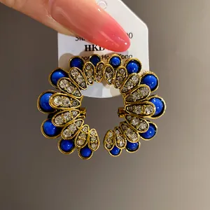 Detail view of vintage palace-style flower stud earrings with royal blue and clear crystals.