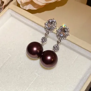 Close-up detail of elegant earrings with brilliant diamonds and dark brown pearls.