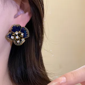 Detailed view of a vintage deep blue floral stud earring with rhinestone accents on a model