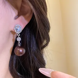 Close-up of elegant silver drop earring with oval crystal and dark chocolate pearl.