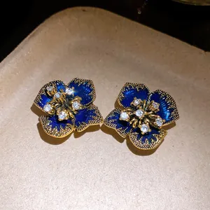 Macro detail of vintage blue enamel flower stud earrings with sparkling center rhinestones