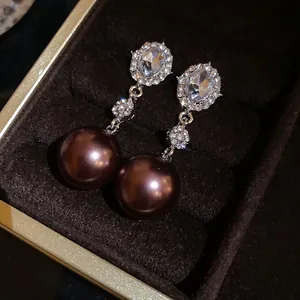 Detailed view of chocolate brown pearl drop earrings with sparkling oval zircon stones.