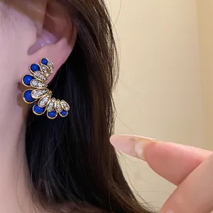 Close-up view of vintage palace style flower earrings with blue beads and diamonds.