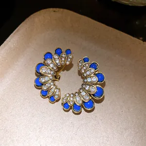Detailed macro view of vintage gold floral stud earrings with blue stones and rhinestones