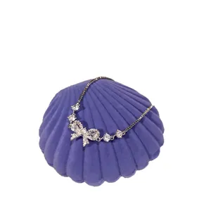 Elegant silver bow zircon bracelet with sparkling stones on purple shell display stand