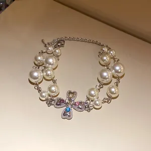 Close-up of a vintage multi-strand pearl bracelet with a heart cross rhinestone pendant