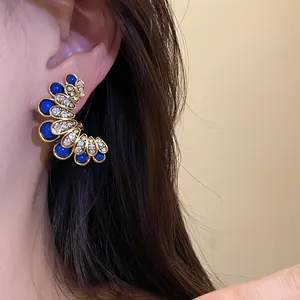 Detailed view of vintage flower earrings with blue stones and clear crystals on model.
