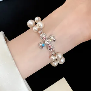 Close-up detail of luxury pearl bracelet with colorful rhinestone clover flower pendant.