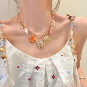 Close-up of gold beach necklace with starfish and shell charms on a model.