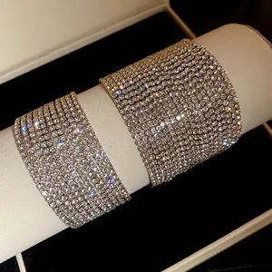 Dettaglio di bracciali a polsino multistrato in strass argentati molto brillanti