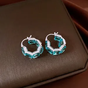 Elegant silver hoop earrings featuring square-cut blue zircons on a dark background