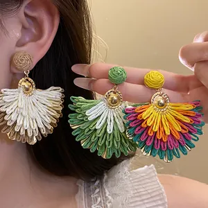 Dettaglio di orecchini colorati in rafia a forma di ventaglio per le vacanze estive.