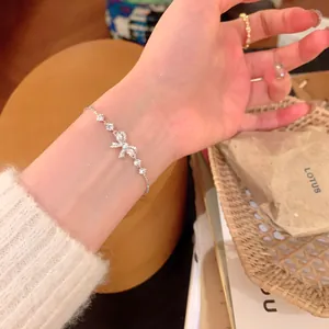 Detailed close-up showing a delicate silver bow knot zircon bracelet on a woman's wrist