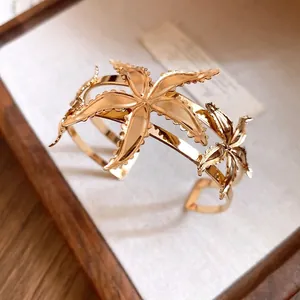 Brazalete abierto vintage de metal dorado con diseño de flor de estrella de mar