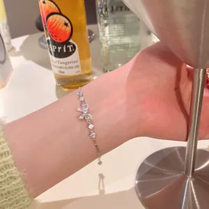 Dainty silver bowknot bracelet with sparkling zircons shown on a female wrist detail