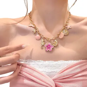 Exquisite gold vacation style necklace featuring pink flower and ocean themed charms