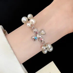 Close-up of vintage pearl bracelet with heart-shaped floral charm and colored rhinestones.