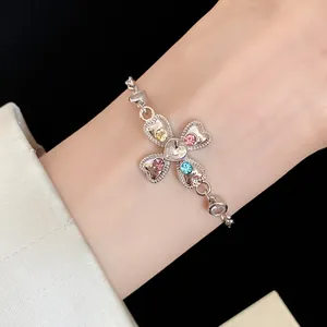 Detailed view of silver heart cross bracelet with multi-colored crystals on wrist