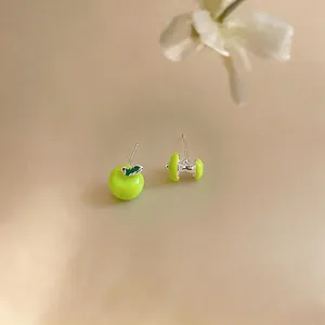 Dettaglio macro di orecchini asimmetrici in smalto verde a forma di mela e torsolo