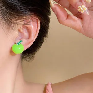 Primo piano dettagliato di un simpatico orecchino a mela in smalto verde indossato sull'orecchio