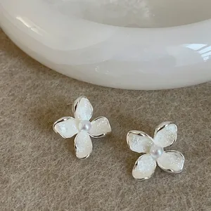 Close-up of elegant flower stud earrings with oil-drop texture and pearl center
