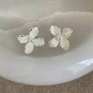 Close-up detail of elegant white flower stud earrings with shimmering petals and pearl centers