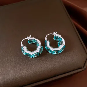 Close-up of retro blue zircon square hoop earrings on brown jewelry box surface.