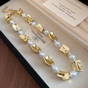 Close-up of vintage pearl necklace with chunky gold-tone links in a jewelry box.