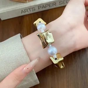 Close-up of vintage pearl and gold geometric bracelet worn on wrist for fashion.